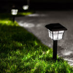 Driveway lights in the grass illuminate the edges of a driveway at night.