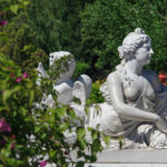 Aphrodite statue in a park with flowering bushes