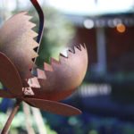 Whimsical man-eating monster plant. Playful, rusty metal garden sculpture.