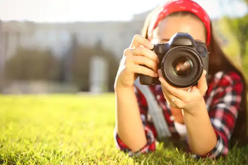 Woman lying in grass with camera