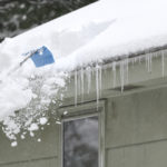 Removing-packed-snow-off-roof-after-snowstorm.