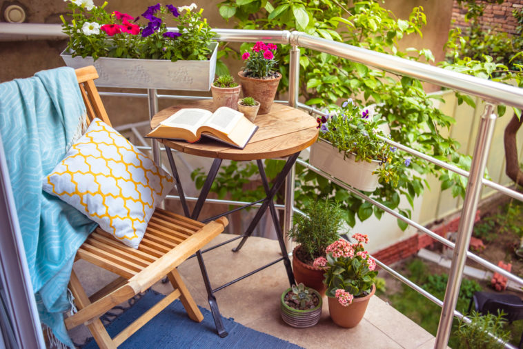 Cozy-balcony-terrace-with-variety-of-potted-flowering-plants-beside-table-and-chair