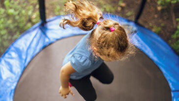 Aerial-view-of-young-girl-with-blond-ponytail-jumping-on-trampoline