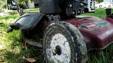 Close-up-shot-of-a-dirty-lawn-mower-covered-in-grass-clippings